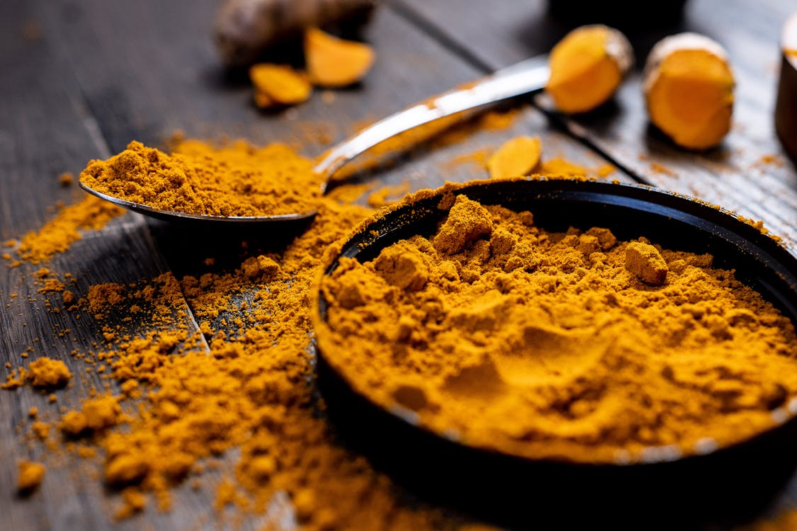 Curcuma en poudre et racine fraîche sur table en bois — ingrédient clé du golden latte Thé Maya